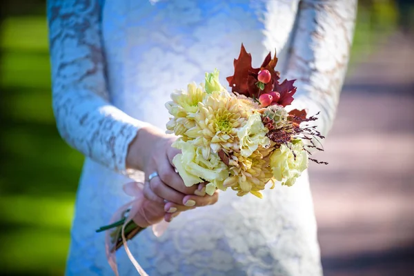 Bride holding colorful elegant modern autumn wedding bouquet in red, marsala, burgundy for a fall wedding.