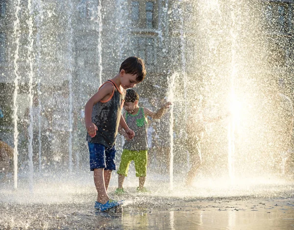 Los niños felices se divierten jugando en la fuente de agua de la ciudad en verano caliente —  Fotos de Stock