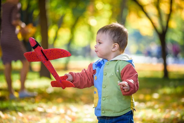 Glückliches Kind spielt mit Spielzeugflugzeug vor blauem Sommerhimmel zurück — Stockfoto