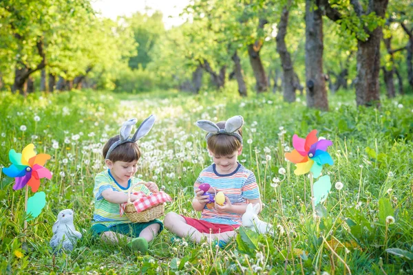 Děti baví a hrát si s velikonoční vajíčka. dva chlapci vesele sedí na trávníku po hon na velikonoční vajíčka — Stock fotografie