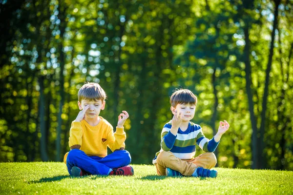 Два белых друга-мальчика, сидящих на свежем зеленом гре — стоковое фото