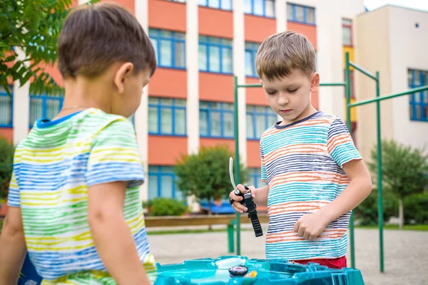 Két fiú játszik egy forgó felső gyerek játék. Népszerű gyermek játék torna. — Stock Fotó