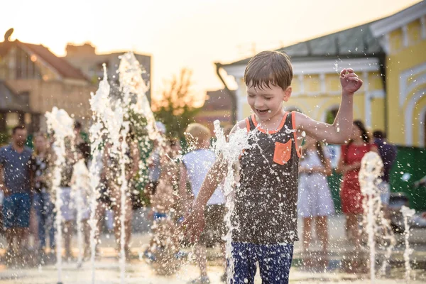 Chico excitado divirtiéndose entre chorros de agua, en la fuente. Verano en la ciudad —  Fotos de Stock