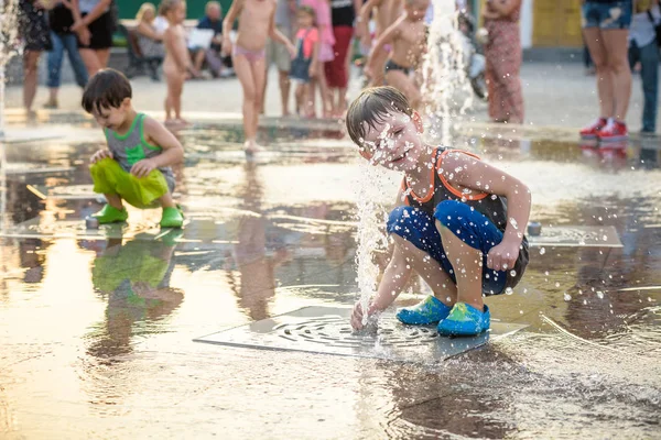 Chico excitado divirtiéndose entre chorros de agua, en la fuente. Verano i — Foto de Stock