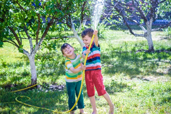 Hermanos divirtiéndose salpicándose con agua en el pueblo —  Fotos de Stock