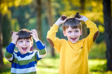 İki Sevimli kardeş küçük çocuk iki büyük çam kozalağı açık havada birlikte oynuyor.