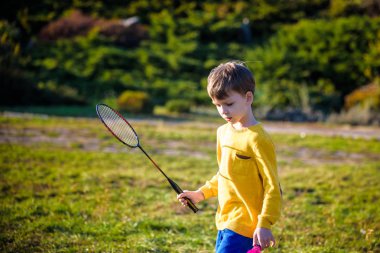 Küçük şirin komik çocuk çocuk üzerinde sıcak yaz parkta oynarken badminton raket ile bahar günü. Etkin açık havada Oyunlar ve eğlence çocuk yaşam tarzı için