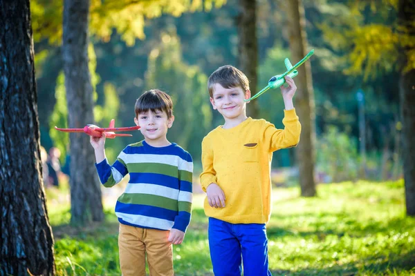 Feliz dos hermanos niños jugando con el avión de juguete contra el fondo azul del cielo de verano. Los chicos tiran espuma en el bosque o en el parque. Mejor concepto de infancia — Foto de Stock