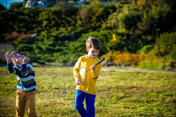 Active preschool girl and boy playing badminton in outdoor court in summer. Kids play tennis. School sports for children. Racquet and shuttlecock sport for child athlete. — Stock Photo, Image