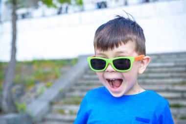 Korkmuş şaşırmış şaşkın karışık beyaz erkek çocuk güneş gözlüklü, pozlar tuğla beyaz duvar arka planı.