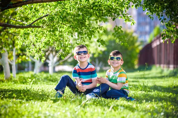 Feliz vacaciones de verano. Dos niños felices en un césped verde en un s —  Fotos de Stock