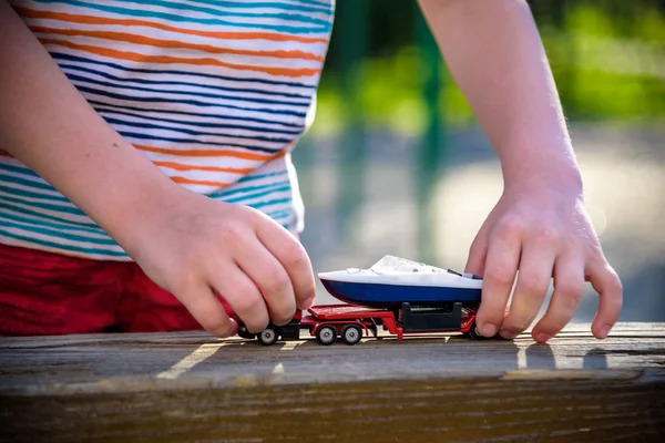 Boy plays with toy cars. Kid playing on the playground alone. Child's daytime fun