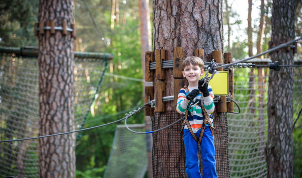 Young cute child boy in summer clothing, safety harness and helm