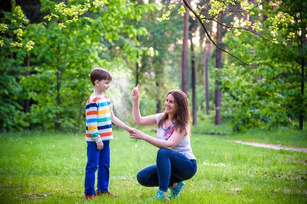 Мати молодої жінки наносить відлякування комах своєму синові перед Ф — стокове фото