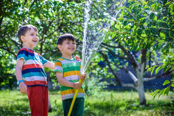 Feliz chico vierte agua de una manguera —  Fotos de Stock