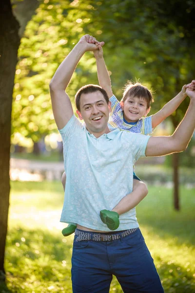 Father and son hugging and playing together in green nature on w