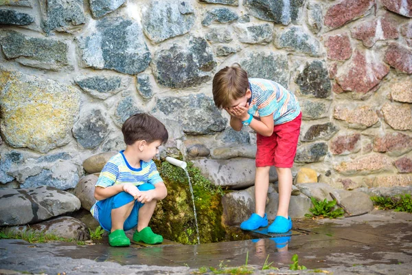 El niño bebe agua fría al aire libre de la tubería —  Fotos de Stock