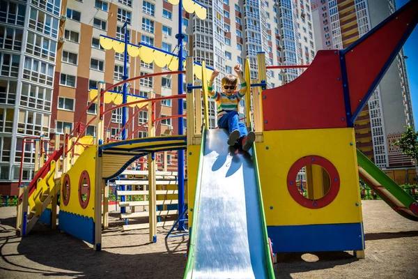 Sommer, Kindheit, Freizeit, Freundschaft und Menschen-Konzept - glücklicher kleiner Junge auf Kinderspielplatz rutschte vom Hügel — Stockfoto