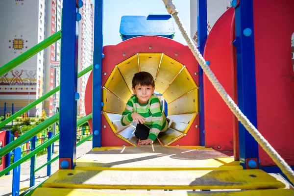 Menino feliz brincando em tubo ou túnel no playground moderno. Férias de verão. Infância feliz e saudável — Fotografia de Stock