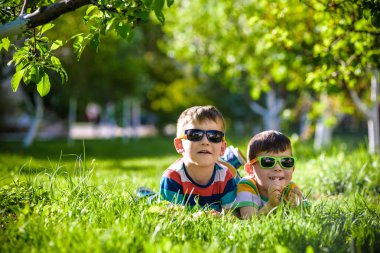 Mutlu gülümseyen erkek kardeş kardeşi çimenlerin üzerinde rahatlatıcı. Kopya alanı görünümüyle kapatın.