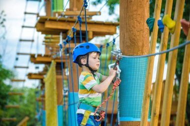 cesur küçük çocuk macera parkı eğlenmek ve cam gülümseyerek