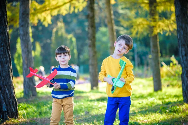 Feliz dos hermanos niños jugando con el avión de juguete contra el fondo azul del cielo de verano. Los chicos tiran espuma en el bosque o en el parque. Mejor concepto de infancia — Foto de Stock