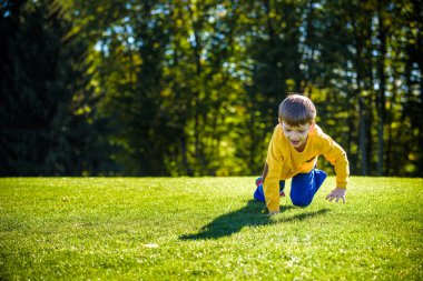 Beyaz çocuk mutlu çocuklar taze yeşil çim çayır üzerinde yukarı tırmanıyor 