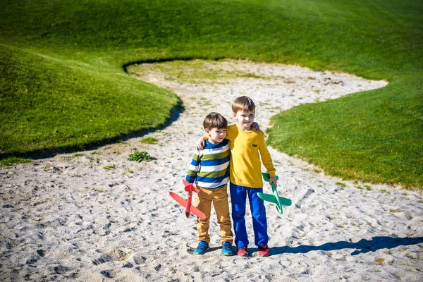 Feliz dos hermanos niños jugando con juguete avión contra azul su — Foto de Stock