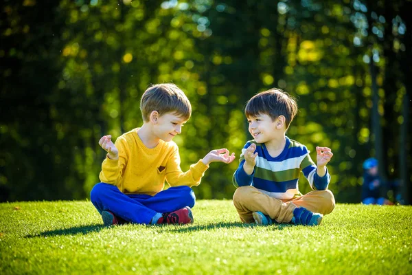 Zwei kaukasische junge bruder freunde sitzen auf frisch grün gr — Stockfoto