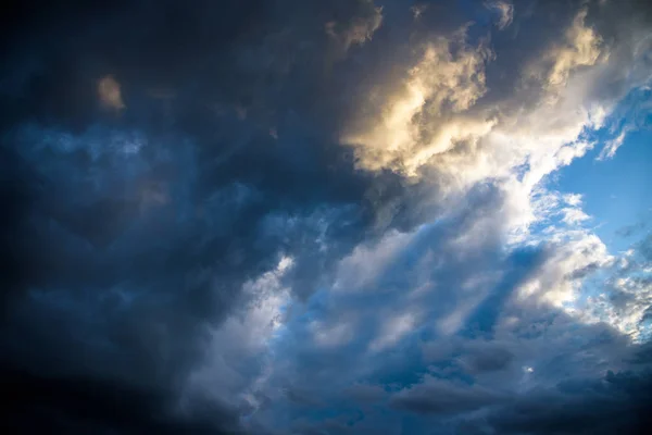 CLOSE UP: Dark grey stormy clouds gather above Lake Maggiore on a calm summer evening. Dramatic shot of clouds covering up the colorful sunlit morning sky. Orange hued evening sky and stormy clouds. — Stock Photo, Image