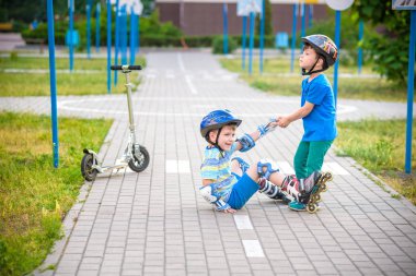 parkta iki erkek, ayağa kalkmak için paten ile çocuk yardım