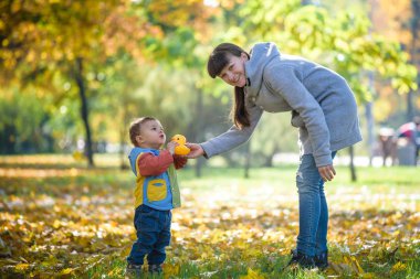 Mutlu genç anne ile bebek sarı sonbahar parkta oynarken 