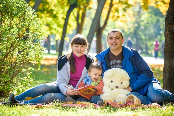Ευτυχισμένη οικογένεια απολαμβάνει πικνίκ φθινόπωρο. Πατέρας μητέρα και γιος κάθονται o — Φωτογραφία Αρχείου