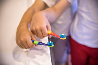 Çocuğun elleri pembe sırtta diş fırçasını tutuyor. Sağlık hizmeti diş konsepti. Metnin için boşluk kopyala
