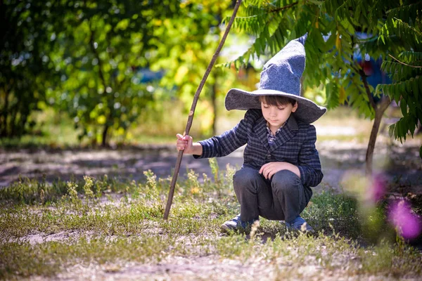 Kleinkind mit Zipfelmütze, das draußen mit Zauberstab spielt. beleuchtet — Stockfoto