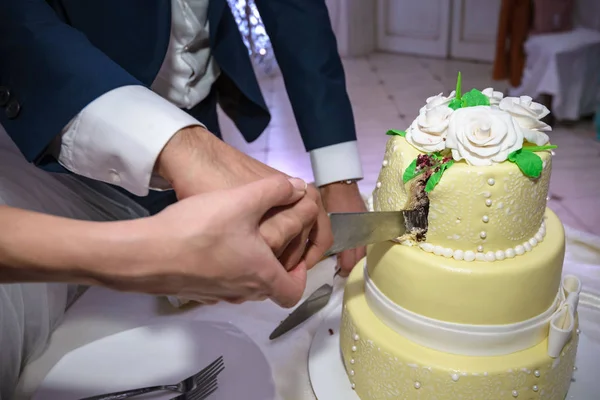 Чудовий весільний торт з нареченим і нареченим, який ріже торт довгим ножем. Квіти справжні, але справді їстівні цукрові квіти. — стокове фото