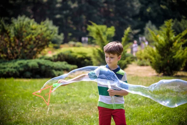 Niño jugando con sus burbujas de jabón juguete en el parque. Actividad infantil. Concepto de primavera — Foto de Stock