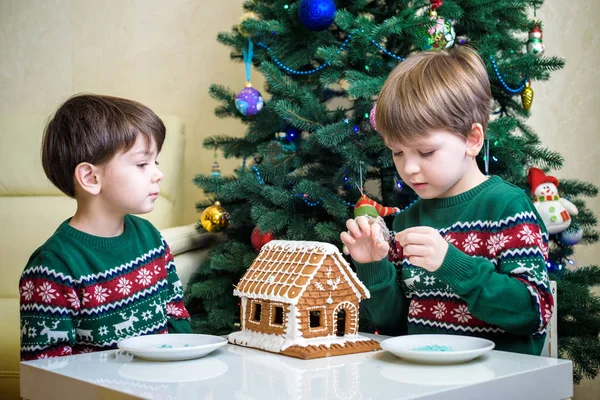 Deux doux garçons, frères, faire la maison de biscuits au pain d'épice, décorer à la maison devant le sapin de Noël, enfant jouant et appréciant, concept de Noël — Photo