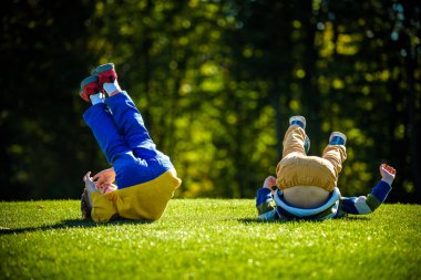 Taze yeşil oynayan iki mutlu çocuk çayır çimen. Çamaşır ve birlikte erkek çocuk gülümseyen iyi arkadaş oldular