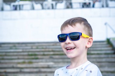 Korkmuş şaşırmış şaşkın karışık beyaz erkek çocuk güneş gözlüklü, pozlar tuğla beyaz duvar arka planı.