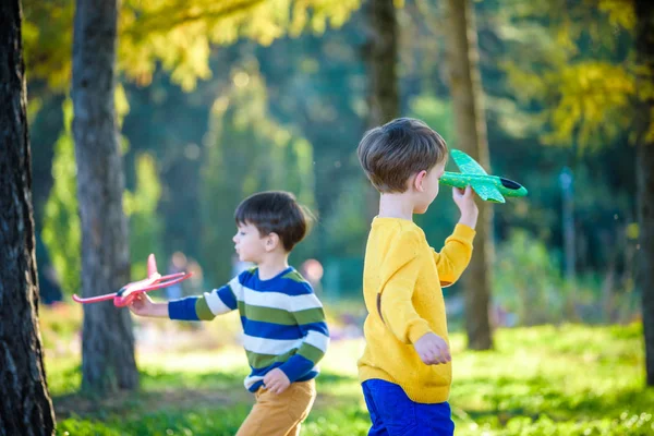 Feliz dos hermanos niños jugando con juguete avión contra azul su — Foto de Stock