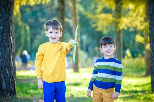 Feliz dos hermanos niños jugando con el avión de juguete contra el fondo azul del cielo de verano. Los chicos tiran espuma en el bosque o en el parque. Mejor concepto de infancia — Foto de Stock