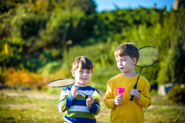 Active preschool girl and boy playing badminton in outdoor court in summer. Kids play tennis. School sports for children. Racquet and shuttlecock sport for child athlete. — Stock Photo, Image