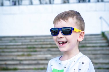 Korkmuş şaşırmış şaşkın karışık beyaz erkek çocuk güneş gözlüklü, pozlar tuğla beyaz duvar arka planı.