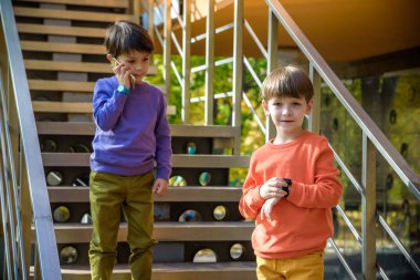 Dışarıdaki merdivenlerde birbirini arayan iki arkadaş. Bir çocuğun cep telefonu, diğerinin GPS 'li akıllı saati var. Çocuk konseptiyle korunma ve güvenli iletişim