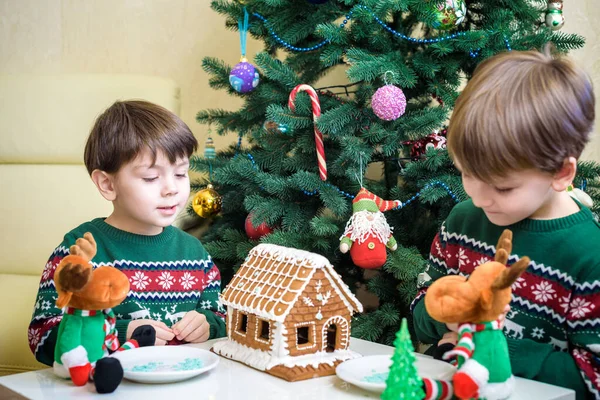 Два милых мальчика, братья, делать пряничное печенье дом, украшать дома перед елкой, ребенок играет и наслаждается, рождественская концепция — стоковое фото