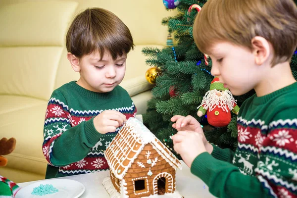 Два милых мальчика, братья, делать пряничное печенье дом, украшать дома перед елкой, ребенок играет и наслаждается, рождественская концепция — стоковое фото