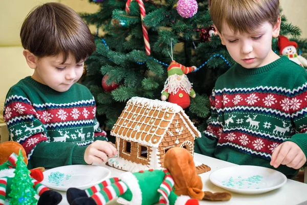 Deux doux garçons, frères, faire la maison de biscuits au pain d'épice, décorer à la maison devant le sapin de Noël, enfant jouant et appréciant, concept de Noël — Photo