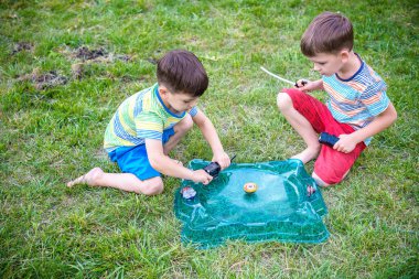 İki erkek ile modern spin üst açık havada oynuyor. Çocuklar için oyun eğlence. Üst, tetikleyici tarafından tetiklenen. Bir turnuva arena ya da savaş alanına sahip çocuklar. Üstten görünüm.