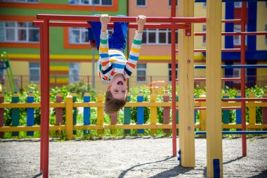 Barda baş aşağı asılı mutlu çocuk, şehirde oyun alanı, açık hava aktiviteleri